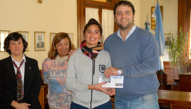 Una estudiante recibe de manos del Intendente su beca y la tarjeta de Debito