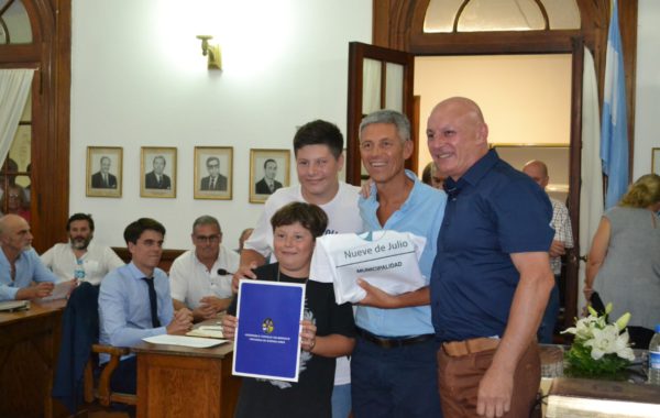 Alberto Capriroli recibiendo su reconocimiento junto a dos de sus hijos y Horacio Delgado
